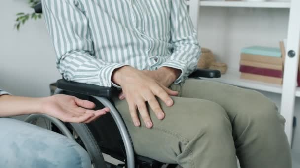 Close-up do homem deficiente em cadeira de rodas segurando as mulheres mão expressando amor e apoio — Vídeo de Stock