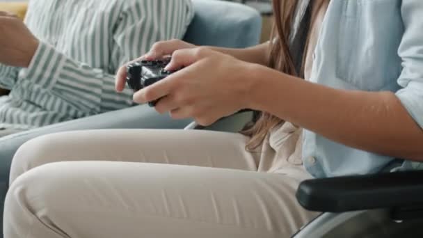 Joyful family paraplegic woman in wheelchair and young man enjoying video game using joysticks — Stock Video