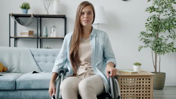 Ritratto di giovane donna sulla sedia a rotelle che indossa abiti casual seduta a casa da sola — Video Stock