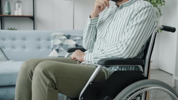 Portrait of lonely disabled guy sitting in wheelchair with sad face thinking indoors at home — Stock Video