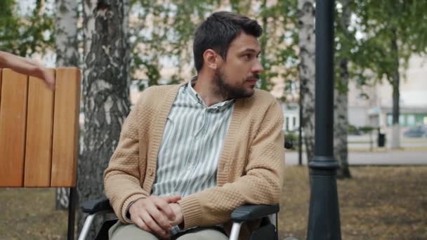 Niepełnosprawny mężczyzna na wózku inwalidzkim spotkanie dziewczyna w parku miejskim trzymając się za ręce uśmiechnięty — Wideo stockowe