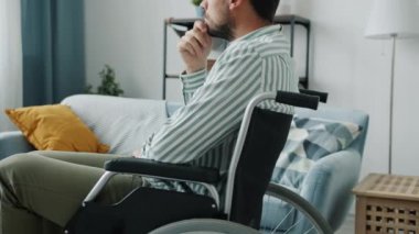 Tekerlekli sandalyedeki düşünceli, engelli kişinin dairede oturup düşünmesi.