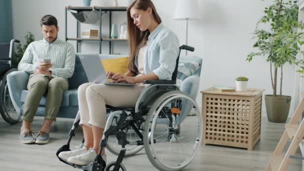 Disabled couple man and woman using modern devices laptop and smartphone working online from home — Stock Video