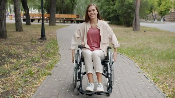 Rallentatore di allegra ragazza paraplegica sulla sedia a rotelle e sorridente nel parco autunnale — Video Stock