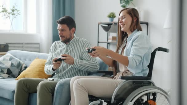 Jovem deficiente jogando videogame com marido ganhando fazendo high-five e rindo — Vídeo de Stock