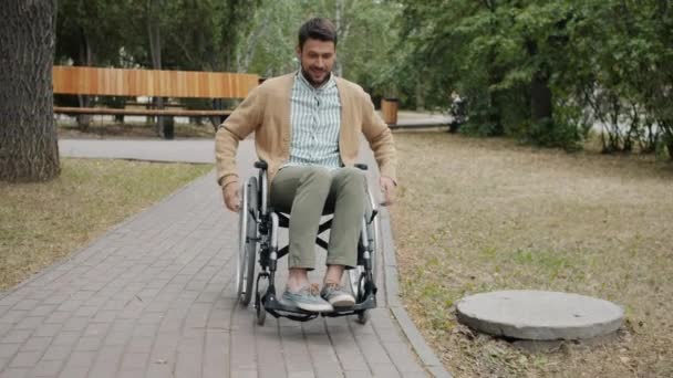 Portrait of joyful paraplegic guy riding wheelchair in city park smile having fun alone — Stok Video
