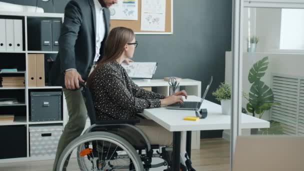 Femme d'affaires en fauteuil roulant parlant à un collègue au bureau discutant d'affaires — Video