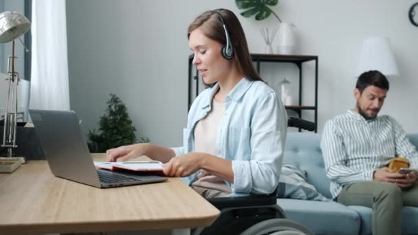 Cheerful disabled woman talking during video call and writing in notebook enjoying online education — Stock Video