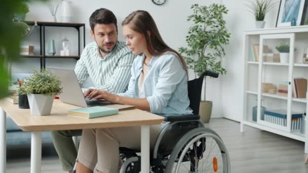 Mujer discapacitada hablando con el marido usando el ordenador portátil y luego obtener buenas noticias abrazos riendo — Vídeos de Stock