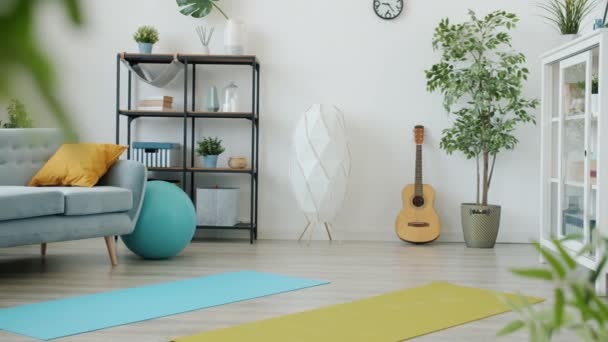 Modern studio apartment with furniture and sports equipment yoga mats fitball and dumb-bells — Stockvideo