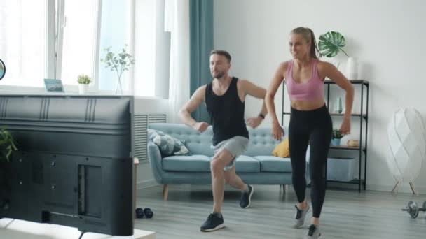 Moderne jongeren trainen thuis tv kijken sportprogramma genieten van lichamelijke activiteit — Stockvideo