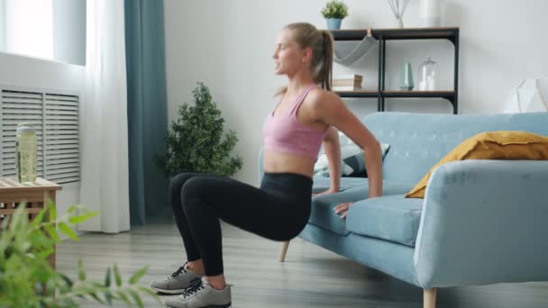 Vrouwelijke vlogger sporter doet sport en spreken kijken naar camera binnen in modern huis — Stockvideo