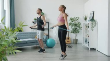 Aktif genç kız ve erkeğin evde ip atlama eğitimini birlikte atlaması.