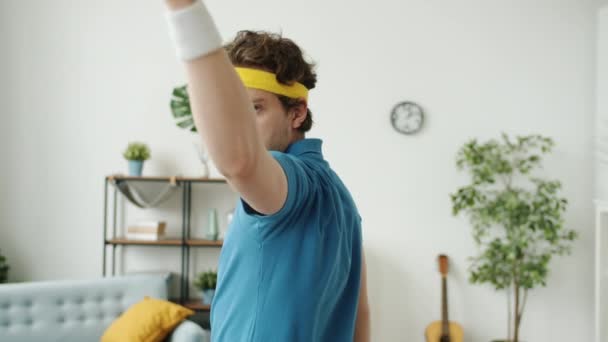 Homme drôle en vêtements de sport rétro faisant geste de la main arme à feu avec des bananes tir regardant la caméra — Video