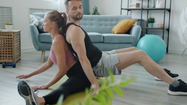 Langzame beweging van mooi paar doen stretching oefeningen in paar geconcentreerd op activiteit — Stockvideo