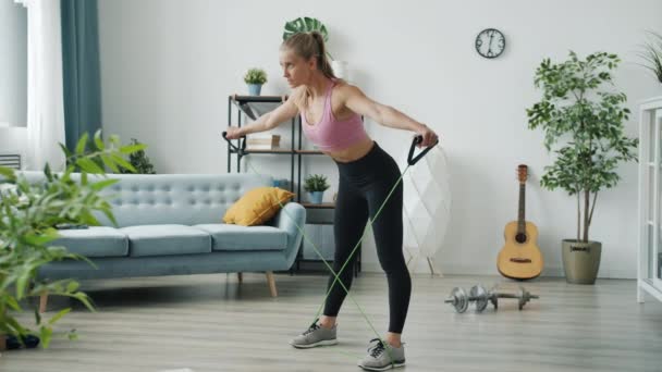 Zpomalení pohybu fit mladá dáma cvičení s strečovou kapelou trénink sám doma — Stock video