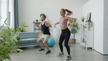 Erkek ve kadın evde birlikte yüksek yoğunluklu antrenman yapıyorlar.