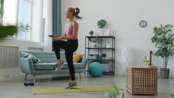 浅谈年轻迷人的金发女子在家里跳跃训练腿时的运动 — 图库视频影像