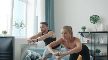 Neşeli genç karı ve koca portresi apartmanda çalışıyor TV 'de spor dersleri izliyor.