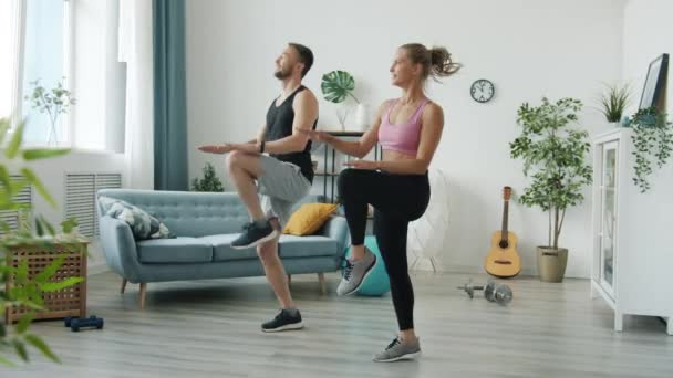Joyful jong paar in sportkleding springen training afvallen binnen in appartement — Stockvideo