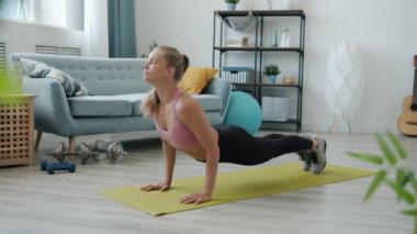 Spor kıyafetli genç bir bayanın evde vücut esneme hareketleriyle yoga yapması.