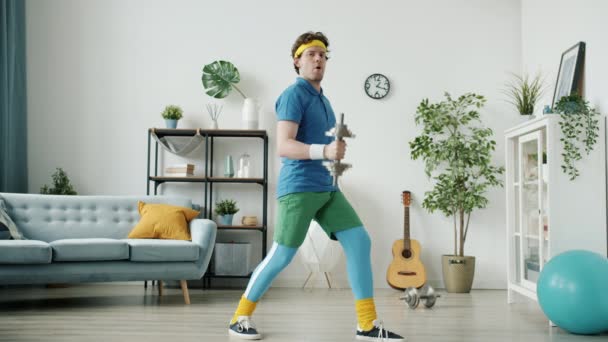 Vtipný retro styl kulturista školení s činky a banány při pohledu na kameru uvnitř v bytě — Stock video