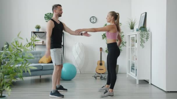 Slow motion van gelukkig man en vrouw kraken hand in hand genieten van training samen in appartement — Stockvideo