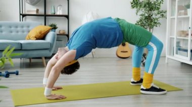 Yengeç pozisyonunda yoga minder eğitimi alan retro kıyafetli sporcu tek başına spor aktivitelerine konsantre oldu.