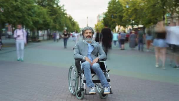 Time lapse portrait de l'homme mature handicapé assis en fauteuil roulant dans la rue piétonne occupée — Video