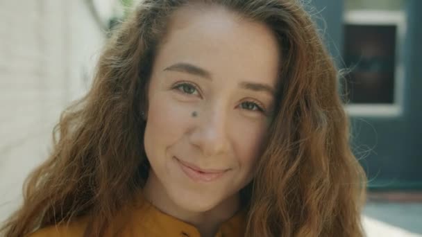Närbild porträtt av glad ung kvinna ler tittar på kameran utomhus i city street — Stockvideo