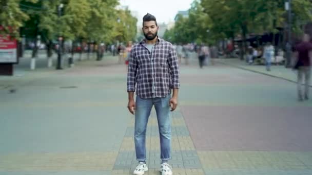 Zoom in time lapse portrait of attractive Middle Eastern man standing alone among people passing by — Video