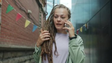 Şehirde cep telefonuyla konuşan neşeli bir kızın portresi.
