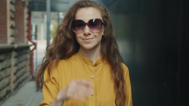 Rallentatore di elegante giovane donna che toglie gli occhiali da sole sorridendo all'aperto in strada — Video Stock
