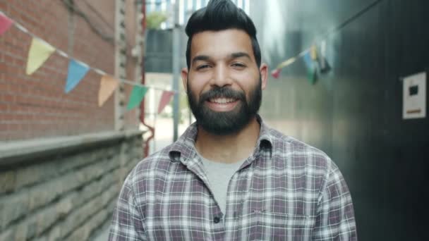 Retrato de un atractivo hombre árabe saludando con la mano y sonriente bienvenida de pie fuera de la ciudad — Vídeo de stock