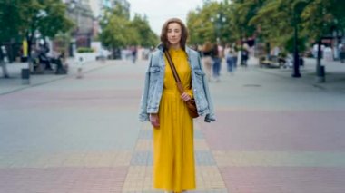 Yoğun caddede yoldan geçen insanların arasında duran çekici genç bayanın zaman geçişi