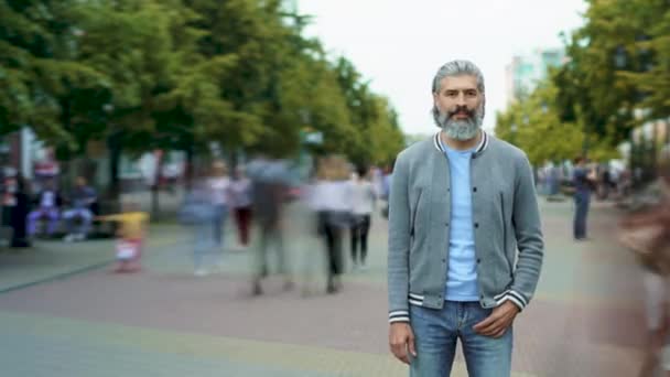 Tijdsverloop van knappe bebaarde man die buiten staat in drukke voetgangersstraat met mensen die rondlopen — Stockvideo