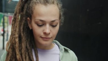 Korkuyla bakan, gözlerini kaldıran ve kameraya bakan mütevazı genç bir kadının yavaş çekim portresi.