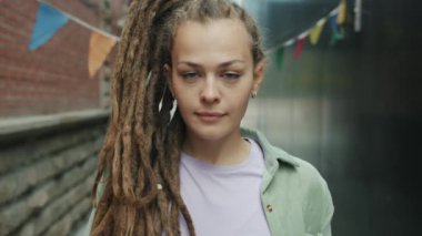 Dışarıda ciddi bir yüzle duran ve kameraya bakıp gülümseyen eşsiz bir kızın portresi.