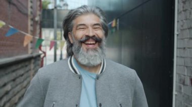 Çekici, olgun bir adamın portresi. Sert bir şekilde gülüyor ve dışarıdaki kameraya bakıyor.