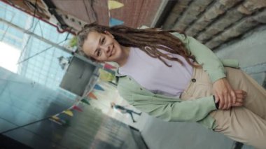 Eşsiz bir kızın portresi. Rastalı gülüyor. Modern şehrin dışında duruyor.