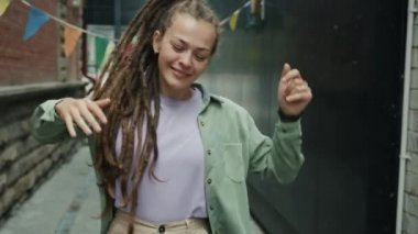 Şehirde dans eden ve gülümseyen güzel genç bir kadının portresi.