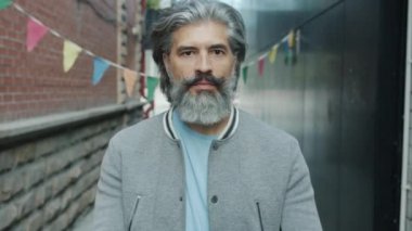 Pembe güneş gözlüğü takan neşeli sakallı adamın portresi ve dışarıda baş parmağını kaldırarak gülmesi.