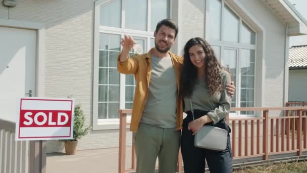 Portrait of man and woman new house owners standing outdoors holding keys hugging smiling — Stock Video