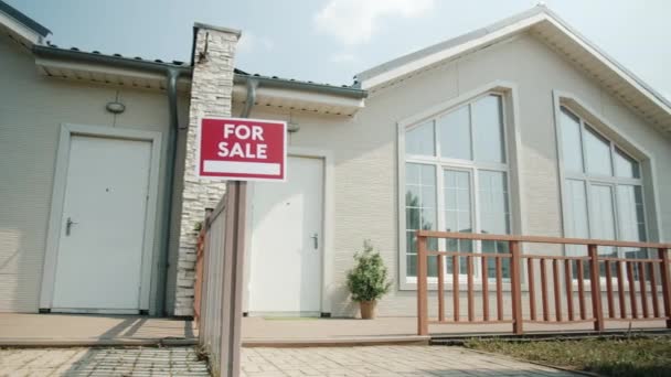 Hermosa casa moderna en la zona suburbana con letrero en venta en el soleado día de verano — Vídeo de stock
