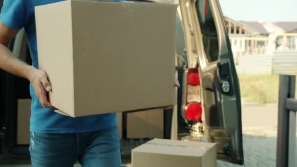 Gesichtsloser Mann bringt allein arbeitenden Karton aus Lieferwagen zum Haus der Kunden — Stockvideo