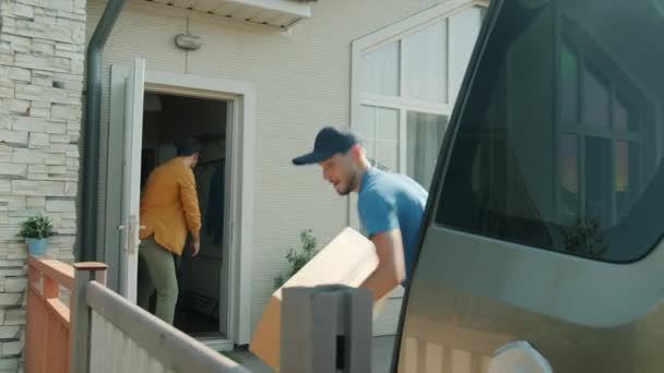 Клієнт кидає посилки до працівника доставки, який завантажує комерційний фургон на відкритому повітрі — стокове відео