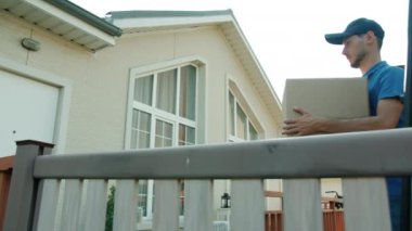 Dışarıdaki müşteriyi bekleyen teslimatçı kargoyu eve götürüyor ve kapıyı çalıyor.