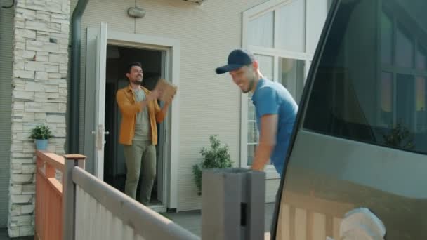 Deliveryman throwing heavy boxes to male client delivering goods and observing social distancing — Stock Video