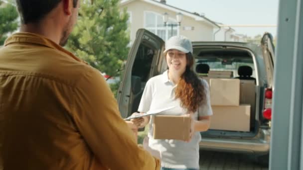 Chica en uniforme entregando paquete dando al cliente que está tomando caja y papel de firma — Vídeos de Stock