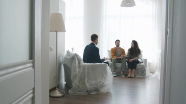 Młoda para klientów rozmawia z agentem nieruchomości w nowym domu — Wideo stockowe